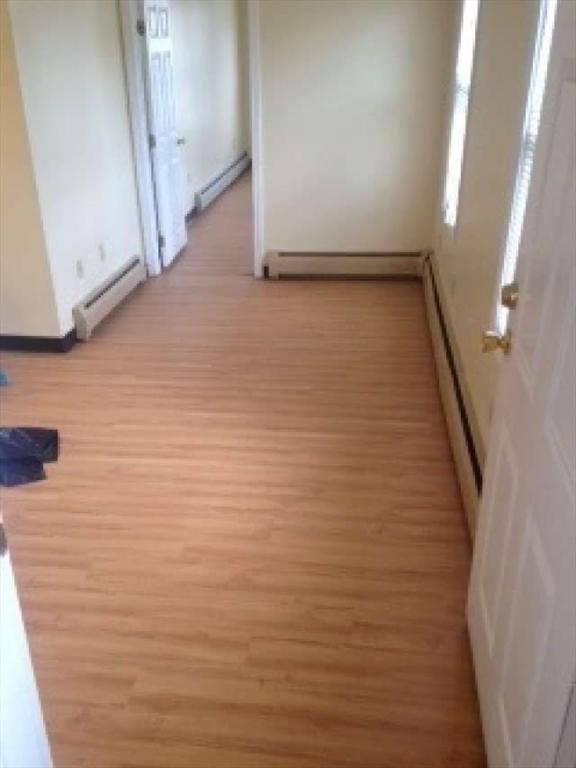 hallway with a baseboard radiator and light hardwood / wood-style floors