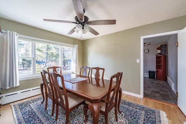 dining area with hardwood / wood-style flooring, a baseboard radiator, and ceiling fan