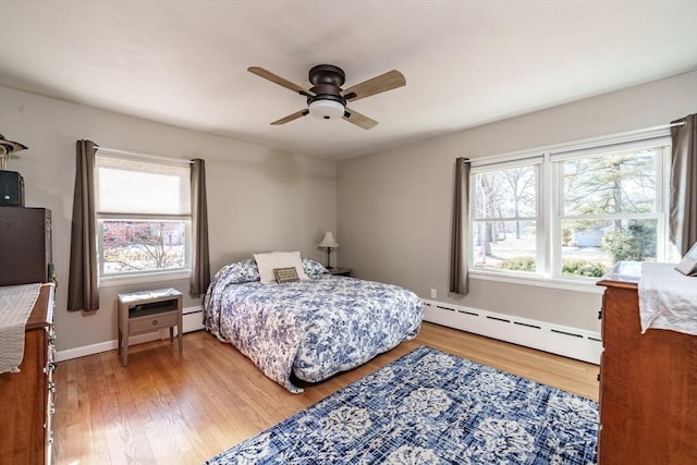 bedroom featuring baseboard heating, ceiling fan, and light hardwood / wood-style floors