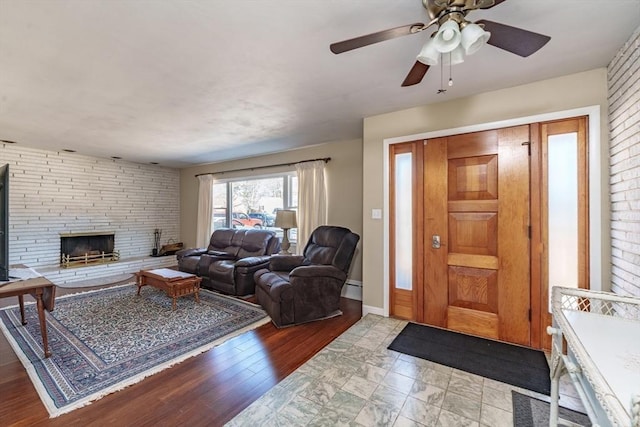 living room with ceiling fan, a baseboard radiator, and a stone fireplace