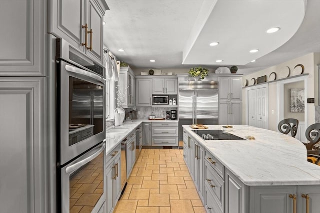 8 Riverside Ter, Easton, MA 02356 - kitchen with gray cabinetry, built in appliances, a kitchen island, tasteful backsplash, and light stone countertops