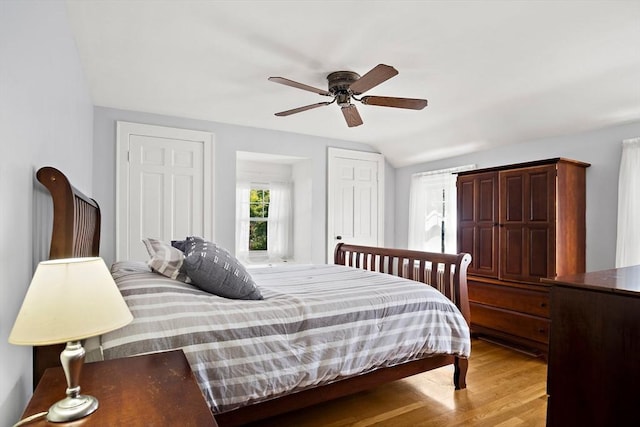 bedroom featuring light wood-style flooring, lofted ceiling, and ceiling fan