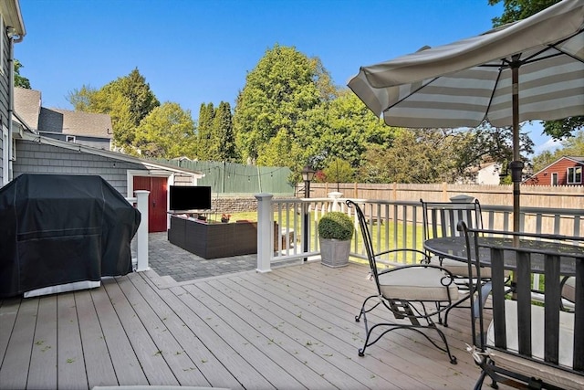 wooden terrace featuring a grill, a fenced backyard, and an outdoor hangout area