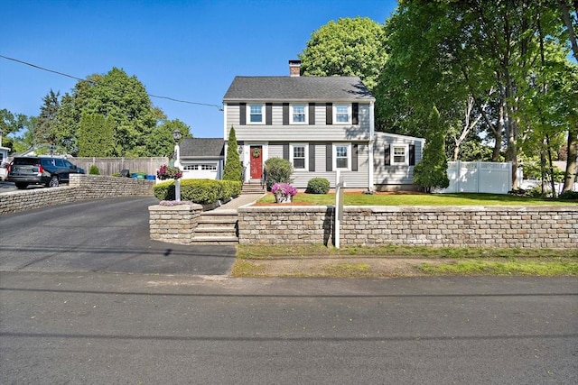 colonial inspired home with fence and a chimney