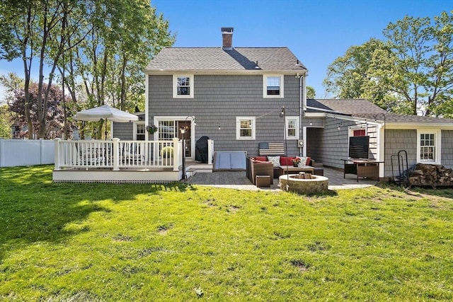 back of house featuring a deck, an outdoor living space with a fire pit, a patio area, and a chimney