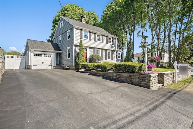 view of front of house featuring a chimney, fence, asphalt driveway, a shingled roof, and a garage