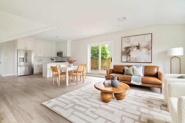 living area with light wood-style flooring and vaulted ceiling