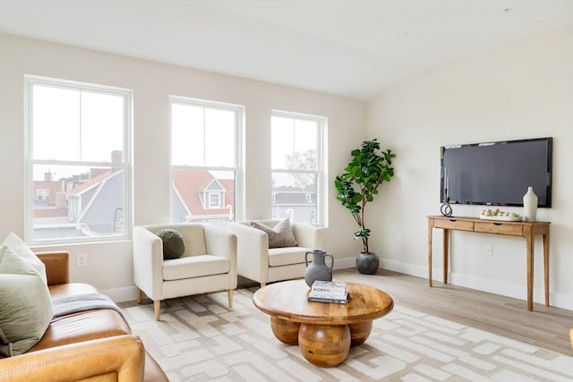 living room with light wood-style flooring, baseboards, and lofted ceiling
