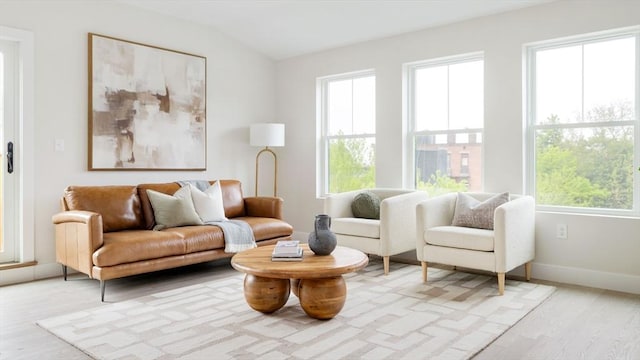 sitting room featuring light wood-style floors, healthy amount of natural light, baseboards, and lofted ceiling