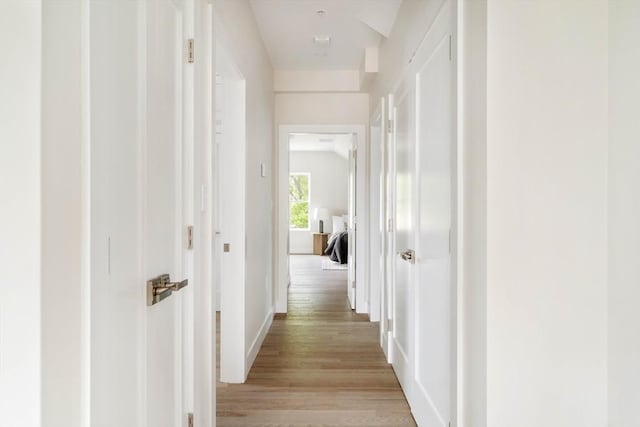 corridor with light wood-type flooring and baseboards
