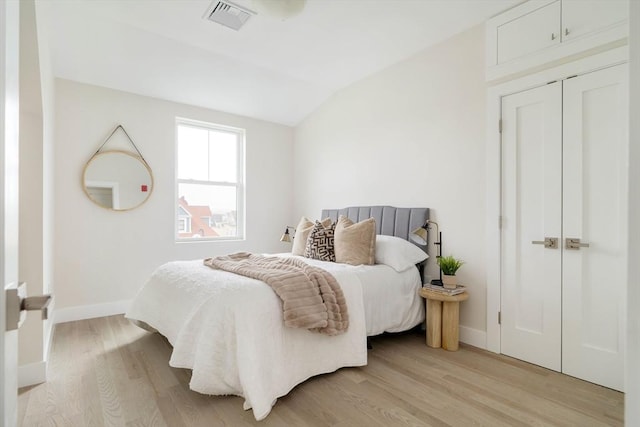 bedroom with light wood finished floors, vaulted ceiling, and baseboards