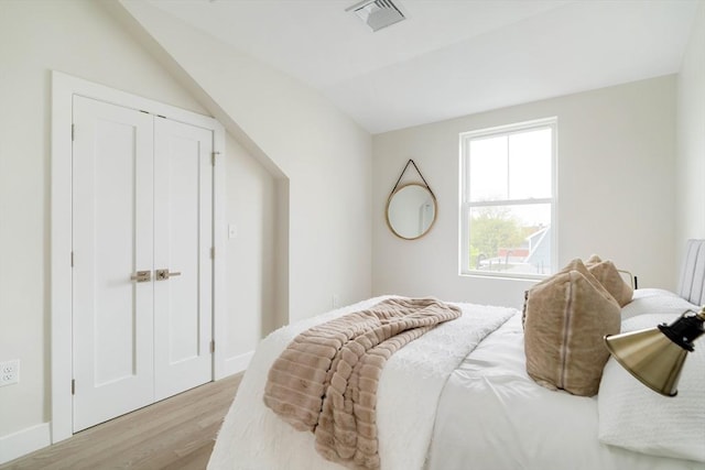 bedroom featuring light wood-type flooring and lofted ceiling