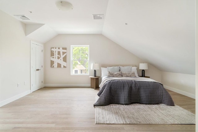 bedroom with light wood-style floors, vaulted ceiling, and baseboards