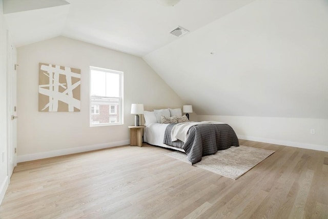 bedroom with vaulted ceiling, light wood-style floors, and baseboards