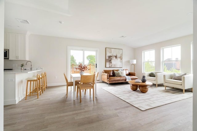 living room with light wood-style flooring, baseboards, and vaulted ceiling