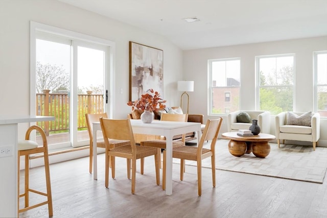 dining area featuring light wood-type flooring, plenty of natural light, and vaulted ceiling