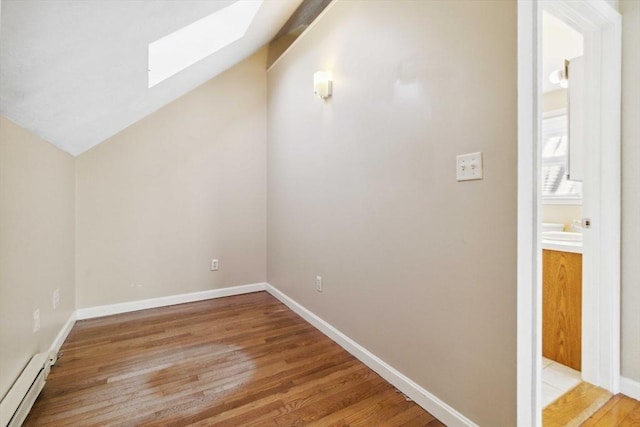 additional living space featuring lofted ceiling with skylight, baseboards, a baseboard heating unit, and wood finished floors