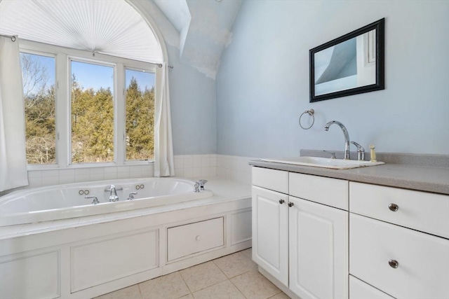 bathroom with a garden tub, vaulted ceiling, vanity, and tile patterned floors