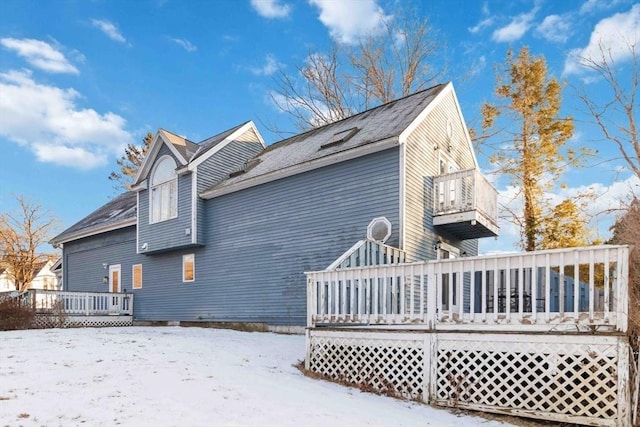 snow covered property with a balcony and a wooden deck