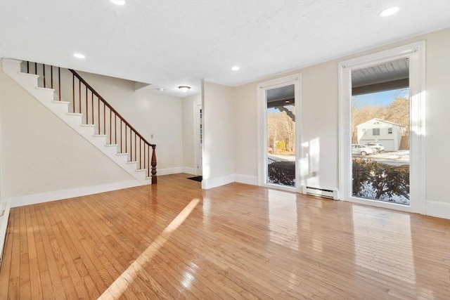 unfurnished living room featuring a baseboard radiator, recessed lighting, stairway, baseboards, and hardwood / wood-style flooring