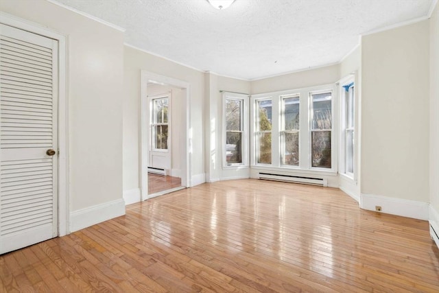 interior space with baseboard heating, wood-type flooring, and crown molding