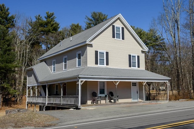 farmhouse-style home featuring roof with shingles and a porch