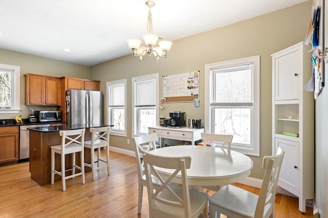 dining room with light wood-style flooring, baseboards, and a chandelier