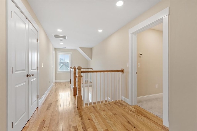 corridor with visible vents, baseboards, light wood-style flooring, recessed lighting, and an upstairs landing