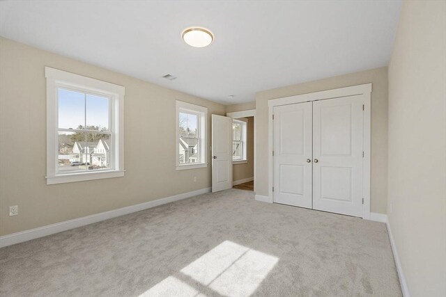 unfurnished bedroom featuring a closet, visible vents, baseboards, and carpet floors