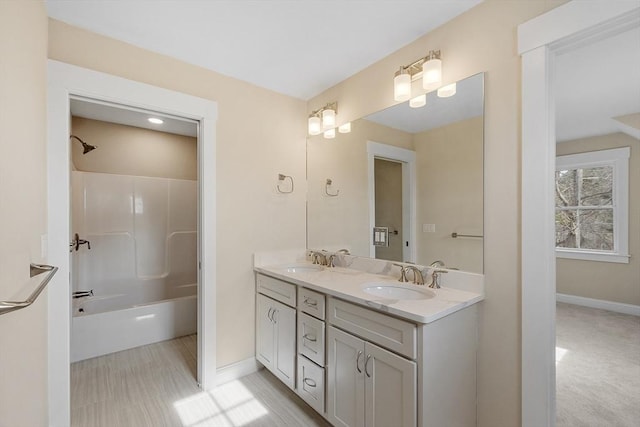 bathroom with double vanity, baseboards,  shower combination, and a sink