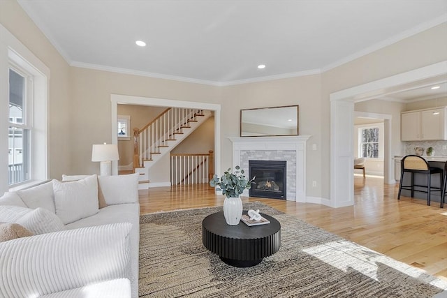 living room with light wood-style flooring, a fireplace, and crown molding