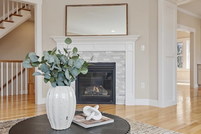 interior details featuring a tiled fireplace, ornamental molding, baseboards, and wood finished floors