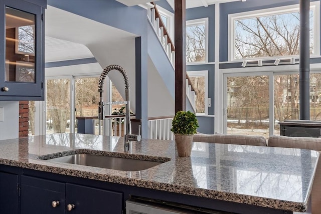 kitchen with sink, blue cabinets, and stone counters