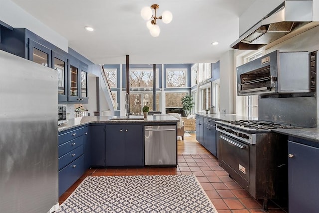 kitchen featuring blue cabinetry, sink, stainless steel appliances, and range hood