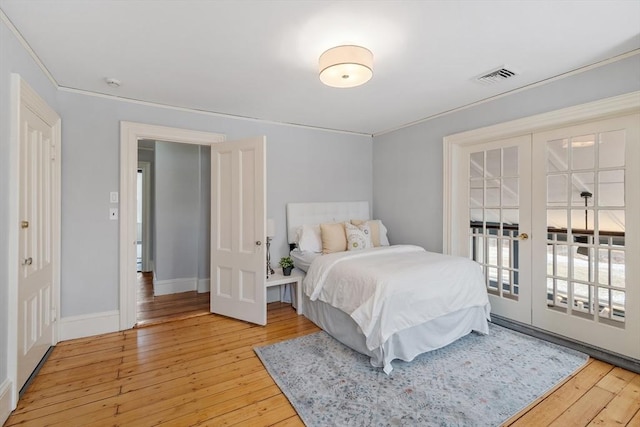 bedroom featuring crown molding, light wood-type flooring, and french doors