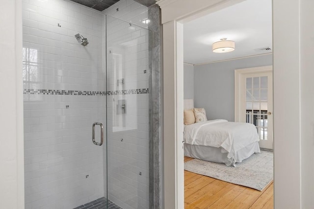 bathroom with a shower with shower door, hardwood / wood-style floors, and ornamental molding