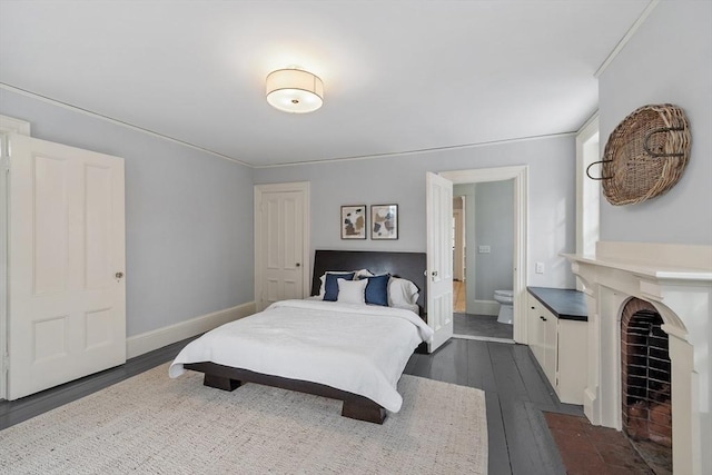 bedroom featuring crown molding, dark wood-type flooring, and ensuite bathroom