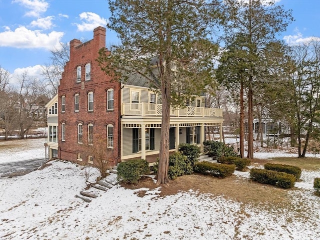 snow covered house featuring a balcony and a porch