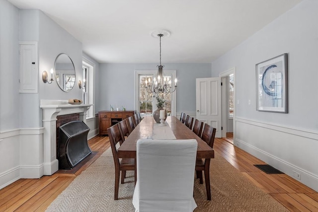 dining room featuring light hardwood / wood-style floors, a chandelier, and a brick fireplace