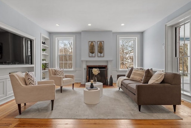 living area featuring built in shelves and light hardwood / wood-style flooring