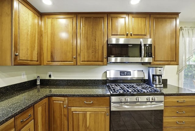 13 Delaval Rd, Worcester, MA 01606 - kitchen with stainless steel appliances, brown cabinetry, tile patterned flooring, and dark stone counters