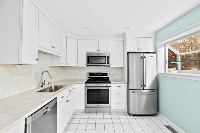 kitchen featuring stainless steel appliances, decorative backsplash, white cabinets, light stone counters, and sink