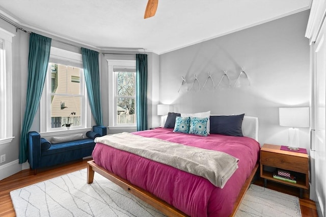 bedroom with baseboards, wood finished floors, and a ceiling fan