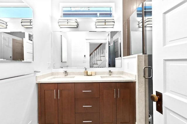 full bath featuring double vanity, a stall shower, and a sink