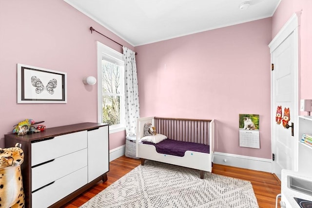 bedroom with baseboards, dark wood-style flooring, and crown molding