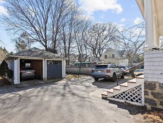 view of car parking with a detached garage and fence