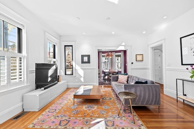 living room with recessed lighting, plenty of natural light, baseboards, and light wood-type flooring