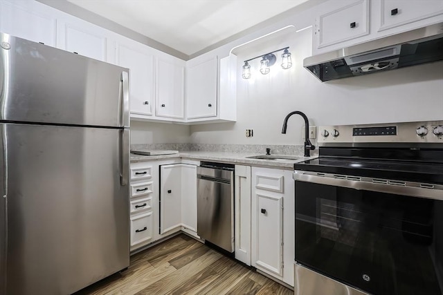 kitchen with sink, appliances with stainless steel finishes, wood-type flooring, ventilation hood, and white cabinets