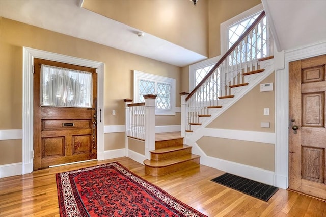 foyer entrance featuring wood-type flooring and a towering ceiling