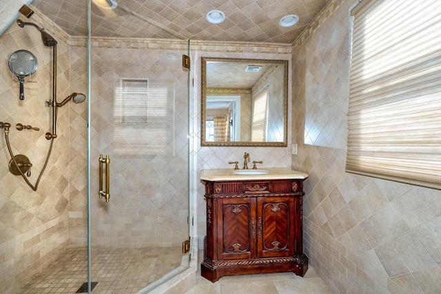 bathroom with an enclosed shower, tile walls, vanity, a healthy amount of sunlight, and tile patterned flooring